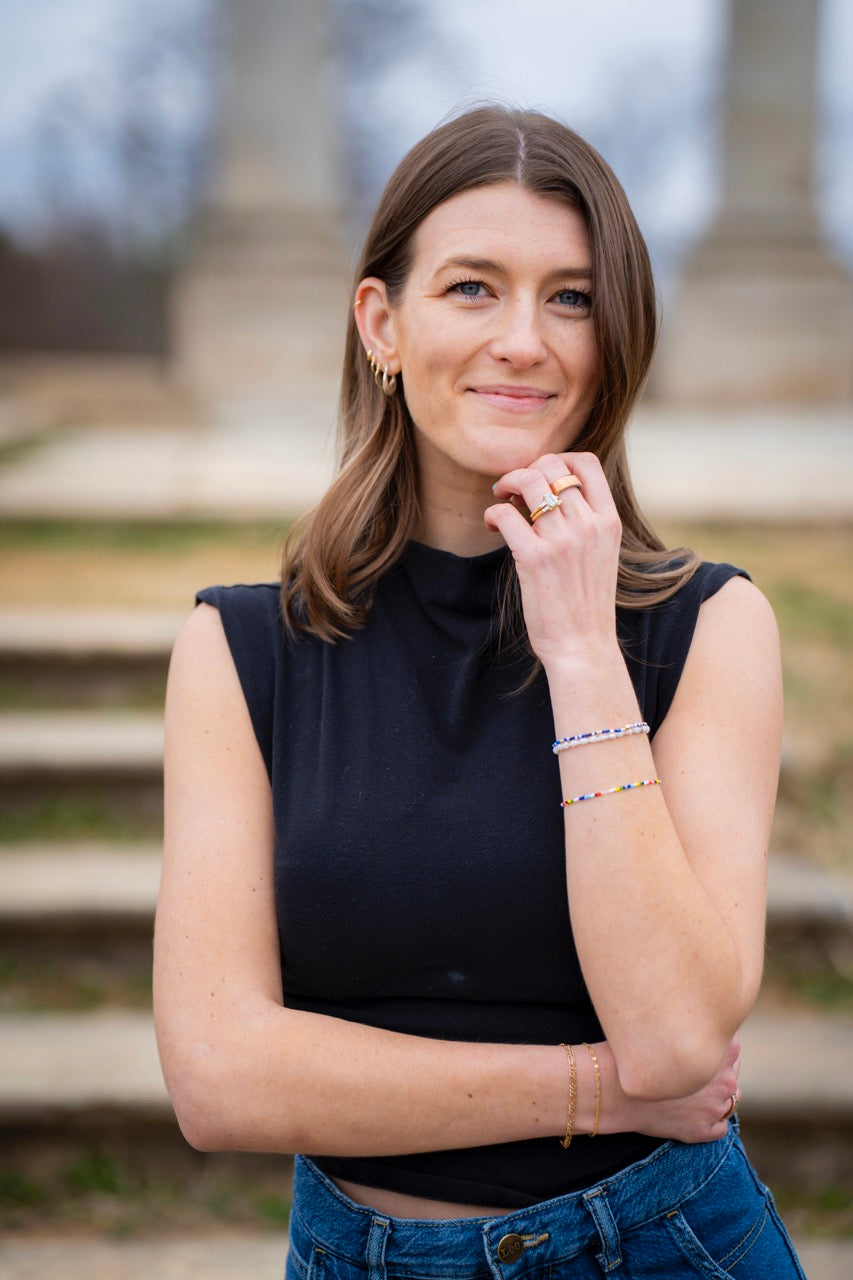 Woman wearing a black sleeveless top and blue jeans with a blurred background